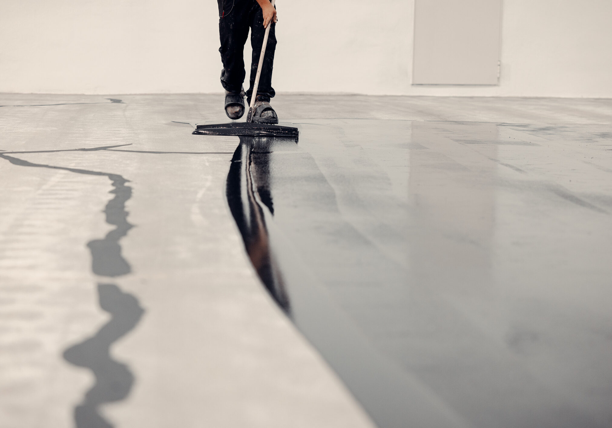 Worker applies grey epoxy resin to a new floor